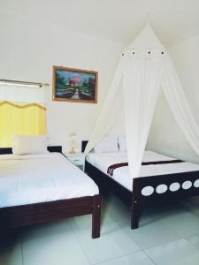 a bedroom with two beds with mosquito nets at Mahakali in Kelimutu