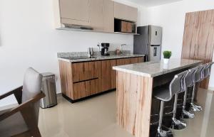 a kitchen with a counter with stools and a refrigerator at Torre Alba 103 in Mazatlán