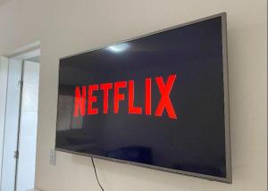 a television with the netflix sign on a wall at Chalé com Varanda Grande e Terraço Vista Mar in Itanhaém