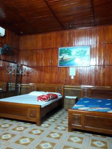 two beds in a room with wooden walls at Nhà nghỉ Hoàng Linh in Bỉm Sơn