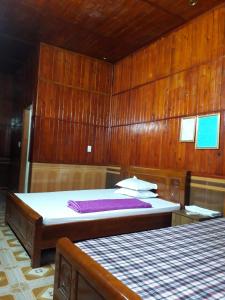 1 dormitorio con 2 camas y paredes de madera en Nhà nghỉ Hoàng Linh, en Bỉm Sơn