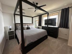 um quarto com uma cama de dossel e uma televisão de ecrã plano em NEW HOME in Private Community with Ocean/Mountain Views. 5 Min. Drive to Beach em Waianae
