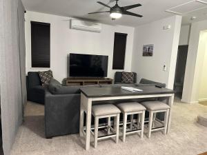 uma sala de estar com uma mesa, um sofá e uma televisão em NEW HOME in Private Community with Ocean/Mountain Views. 5 Min. Drive to Beach em Waianae