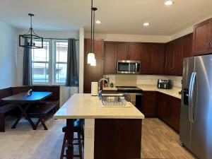 a kitchen with wooden cabinets and a stainless steel refrigerator at NEW HOME in Private Community with Ocean/Mountain Views. 5 Min. Drive to Beach in Waianae