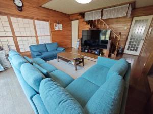 a living room with a blue couch and a tv at Biei Snow House - Vacation STAY 14827 in Biei