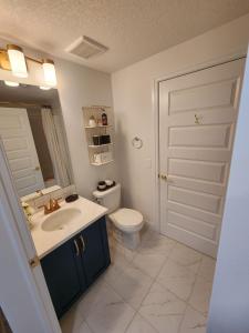 uma casa de banho com um WC, um lavatório e um espelho. em Luxury Condo Near Calgary Airport em Calgary