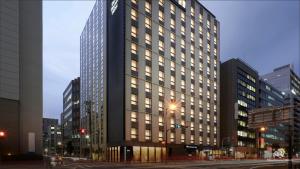 een hoog gebouw met veel ramen in een stad bij Daiwa Roynet Hotel Osaka Sakaisuji Honmachi PREMIER in Osaka