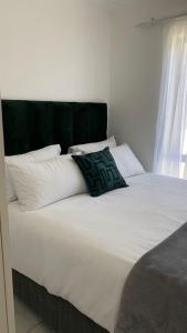 Una cama blanca grande con una almohada verde. en Comfort and Style, en Ciudad del Cabo