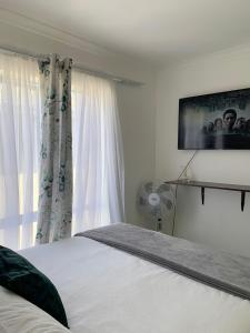 1 dormitorio con cama blanca y ventana en Comfort and Style, en Ciudad del Cabo