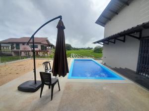 a umbrella and a chair next to a swimming pool at Freesia Haus in Kota Bharu