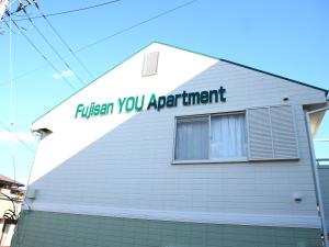 Um edifício branco com um cartaz que diz para dar descarga ao seu aprendiz. em 富士山結アパートメント em Fujiyoshida