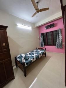 een slaapkamer met een bed en een plafondventilator bij The best enclave in Chennai
