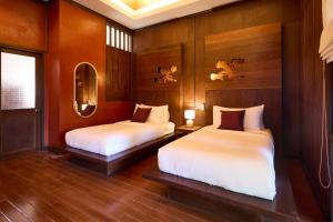 two beds in a room with wood paneled walls at Jambolan Chiangmai in Chiang Mai