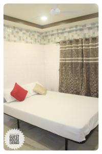 un letto bianco con due cuscini rossi sopra di Paradise Guest House a Chennai