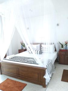1 dormitorio con cama con dosel y cortinas blancas en Nethu villa, en Galle