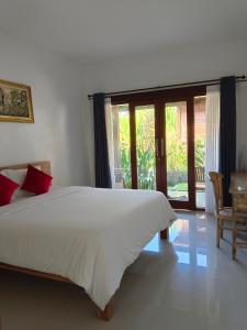 Un dormitorio con una cama blanca y una ventana grande. en Rahma Guesthouse, en Canggu
