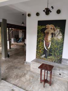 a painting of an elephant on a wall next to a table at Silva Rest in Unawatuna