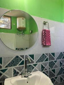 a bathroom with a mirror and a sink at Pinehill cottage in Jibhi