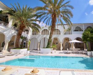 a swimming pool in front of a building with palm trees at Riad Palais Blanc & Spa in Marrakech