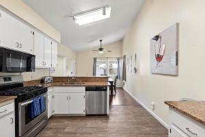 a kitchen with white cabinets and a counter top at Pacific Paradise - Large Patio, Hot Tub, Short Walk to Beach, & Parking in San Diego