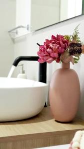 eine rosa Vase mit Blumen auf einer Theke neben einem Waschbecken in der Unterkunft Appartamento Garden in Riccione