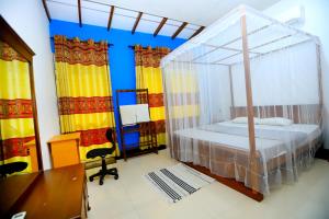 a bedroom with a canopy bed and a desk at villa surendra in Weligama