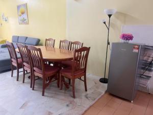 a dining room table with chairs and a refrigerator at Leisure Homestay in Kampong Peruntun