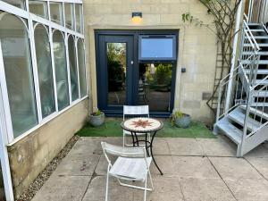 a patio with a table and chairs in front of a door at The Retreat, luxury apartment in Bath with parking in Bath