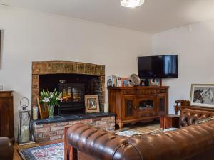 a living room with a couch and a fireplace at Burwood Cottage in Rotherfield Peppard