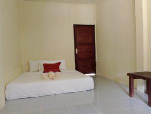 1 dormitorio con cama blanca y almohada roja en MBE BALENG KU, en Mangsit