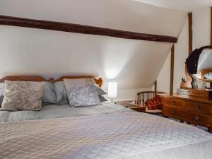 a bedroom with a large bed and a dresser at Burwood Cottage in Rotherfield Peppard