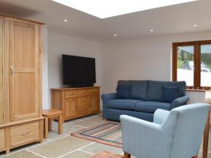 een woonkamer met een blauwe bank en een tv bij Lower Netherdowns in Littleham