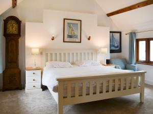 een slaapkamer met een groot wit bed en een klok bij Lower Netherdowns in Littleham