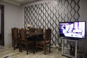 uma sala de jantar com uma mesa com cadeiras e uma televisão em Comforthome em Yerevan