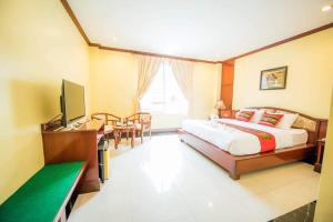 Dormitorio con cama, escritorio y TV en Soubundith Hotel en Pakse