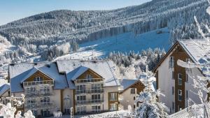 un edificio nella neve con una montagna sullo sfondo di Czarna Góra Resort Apartament na Skarpie a Sienna