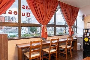 ein Esszimmer mit einem Tisch, Stühlen und Fenstern in der Unterkunft Almas Guest House(アルマス） in Nagasaki