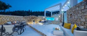 a patio with a couch and chairs and a stone wall at Dion Villa Zakynthos Greece in Agios Nikolaos