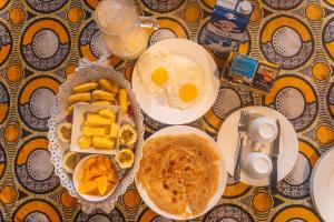 a table topped with plates of breakfast foods and pancakes at Kiungani Lodge in Jambiani