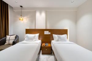 Pokój hotelowy z 2 łóżkami i krzesłem w obiekcie Hotel Vilvah w mieście Coimbatore