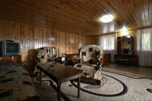 ein Wohnzimmer mit 2 Stühlen, einem Tisch und einem TV in der Unterkunft Nika house in Zqaltubo
