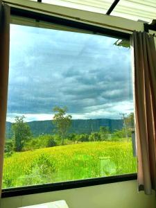 a window with a view of a field of grass at Heaven Hill Camping in Ban Thung Na
