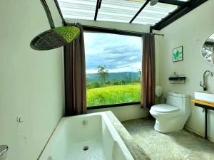 a bathroom with a tub and a toilet and a window at Heaven Hill Camping in Ban Thung Na