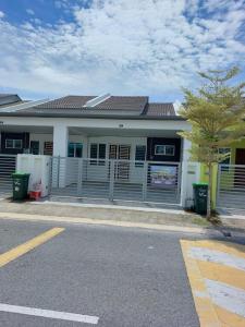 a white building with a gate and a street at Homestay Taman Kota Emas 