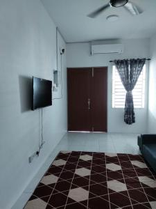 a living room with a television and a door with a window at Homestay Taman Kota Emas 