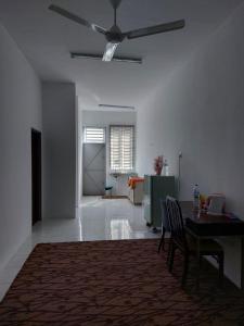 a living room with a table and a ceiling fan at Homestay Taman Kota Emas 