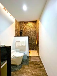 a bathroom with a toilet and a brick wall at Widya Luxury House in Ubud