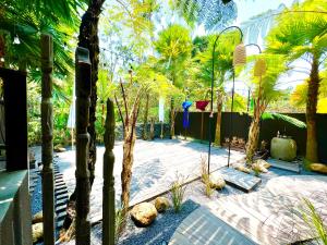 a garden with palm trees and benches and a fence at Widya Luxury House in Ubud