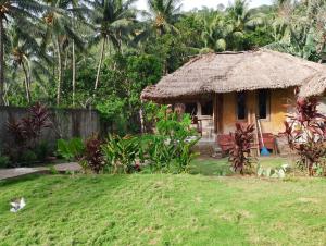 a small hut with a grass roof in a yard at MBE BALENG KU in Mangsit