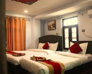 1 dormitorio con 2 camas y almohadas rojas y blancas en Hotel Darshan, en Surkhet